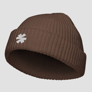 A brown ribbed knit beanie hat with a small white embroidered asterisk logo on the front cuff, shown against a light gray background.
