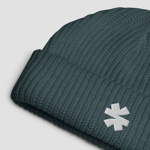 Close up details of a ribbed knit beanie with a white embroidered asterisk logo on a light gray background.