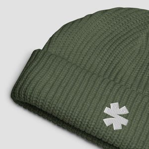 Close-up details of a ribbed knit beanie with a small white embroidered asterisk logo set against a light gray background.