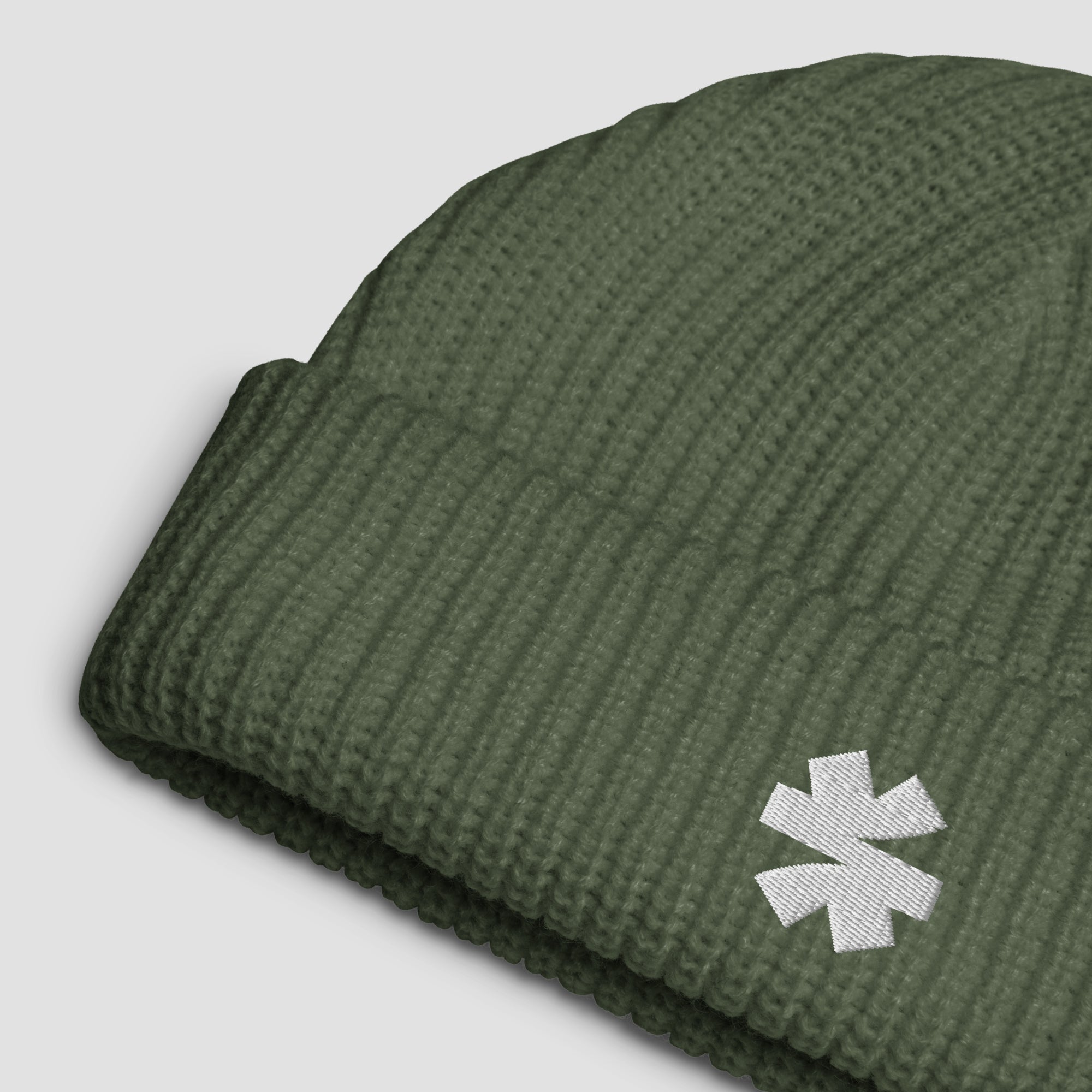 Close-up details of a ribbed knit beanie with a small white embroidered asterisk logo set against a light gray background.