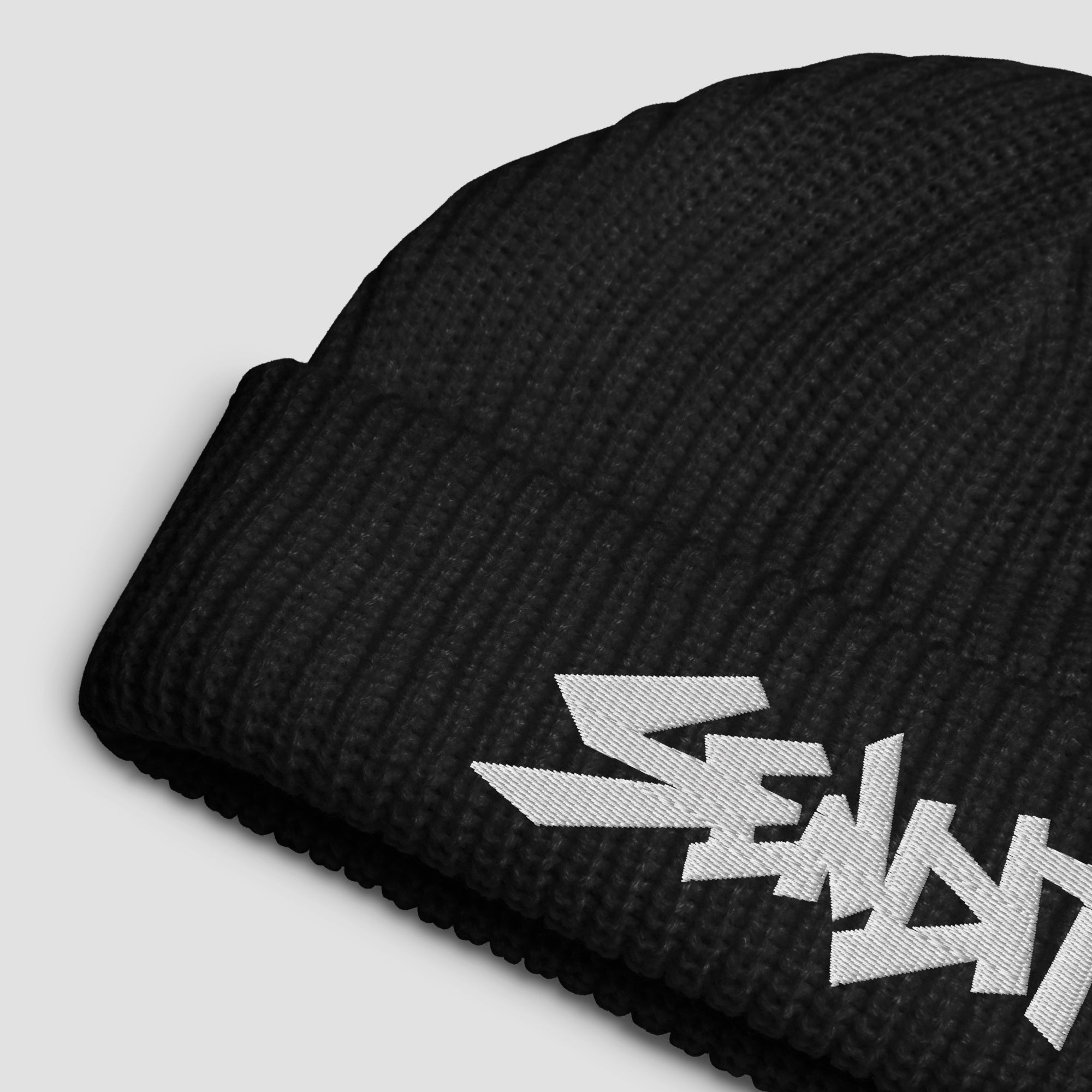 A close-up of a black ribbed knit beanie with a white embroidered stylized 'SENDIT' logo on the cuff, photographed on a light gray background.
