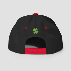 The back of a black snapback cap featuring a red adjustable strap, red eyelets, and a green asterisk in the center.