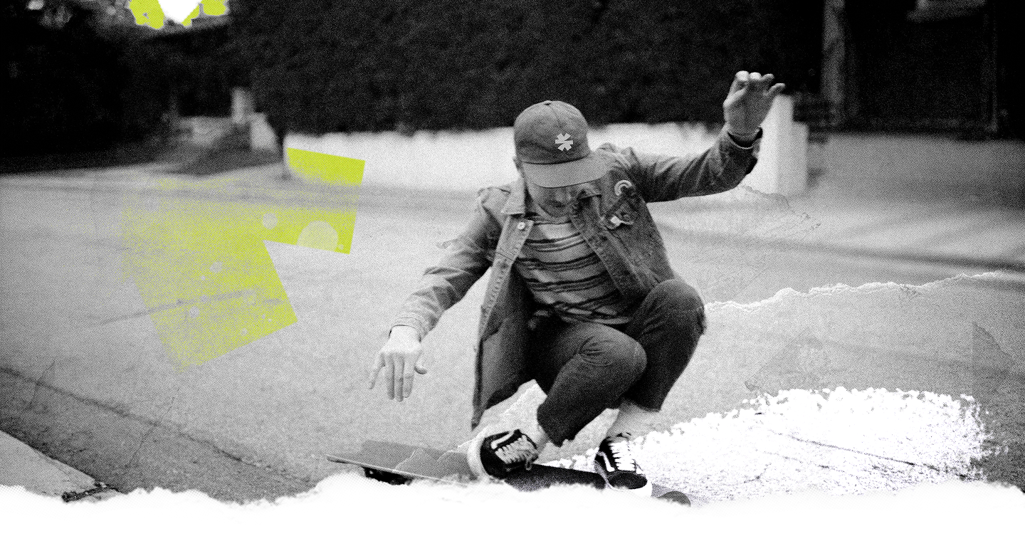A person crouching on a skateboard in an outdoor street setting, shown in black and white with bright neon yellow graphic overlays.