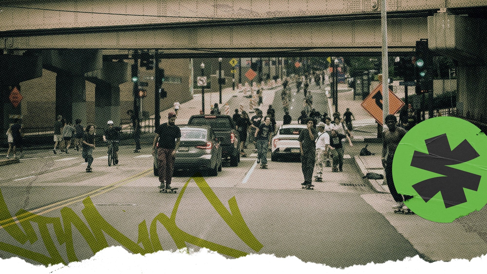 A street scene under an elevated highway overpass with multiple people riding skateboards and walking, cars on the road, graffiti on the pavement, and a green circular graphic overlay in the lower right corner.
